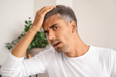 Evde gri saçlı stresli bir adam var.