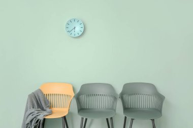 Renkli duvarın yanında ekose ve saati olan sandalyeler.