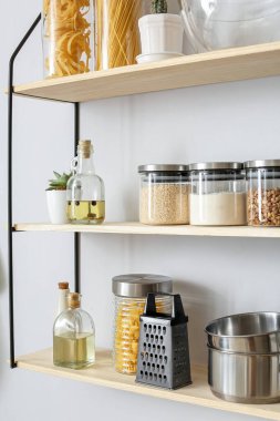 Raflarda mutfak gereçleri ve ürünlerle dolu cam kavanozlar.