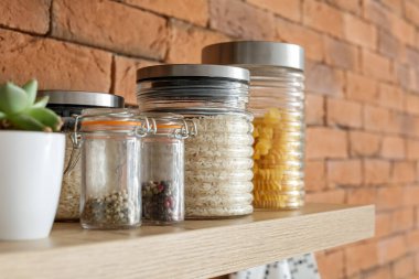 Mutfak rafında baharatlı cam kavanozlar ve ürünler.