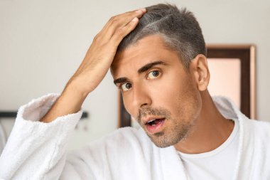 Evde gri saçlı stresli bir adam var.