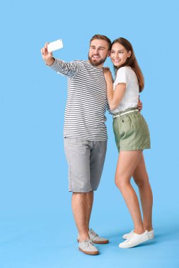 Renkli arka planda selfie çeken genç çift.