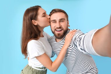 Renkli arka planda selfie çeken genç çift.