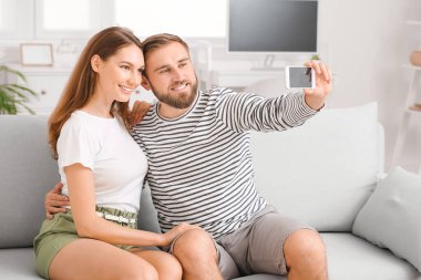 Genç çift evde selfie çekiyor.