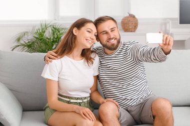 Genç çift evde selfie çekiyor.