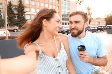 Genç çift dışarıda selfie çekiyor.