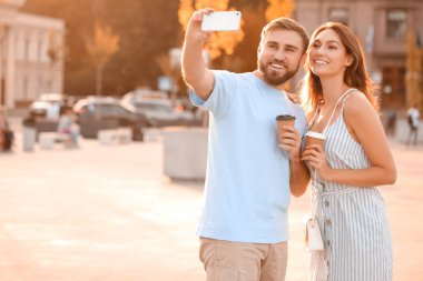 Genç çift dışarıda selfie çekiyor.