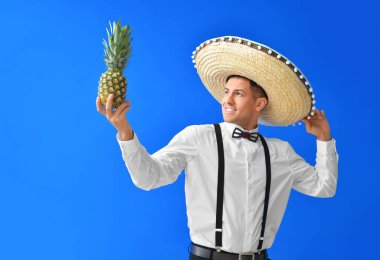 Sombrero şapkalı yakışıklı genç adam ve ananas rengi arka planda.