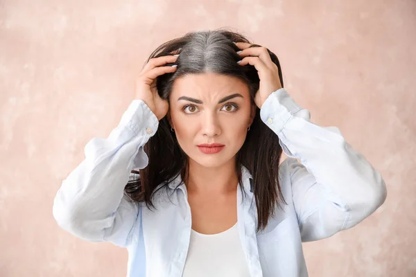 Stressed woman with graying hair on color background