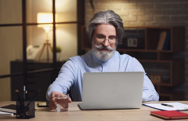 Senior businessman working in office at night