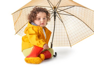 Yağmurluk giyen ve beyaz arka planda şemsiyesi olan tatlı bir kız.