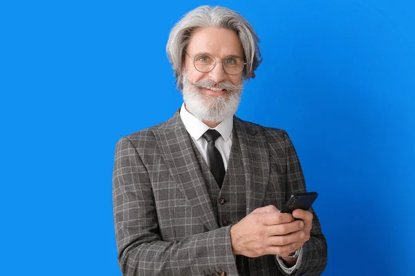 カラー背景に携帯電話を持つシニアビジネスマンの肖像画 — ストック写真