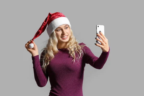 戴着圣诞礼帽 身披浅色背景手机的年轻漂亮女子 — 图库照片
