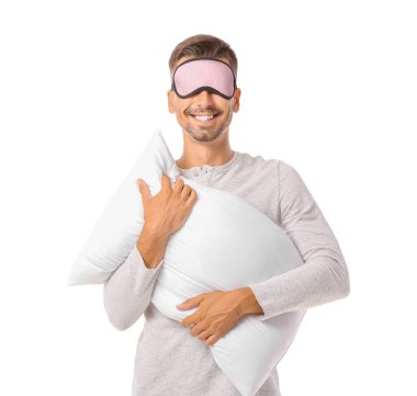 Beyaz arka planda yastığı olan uyku maskeli genç bir adam.