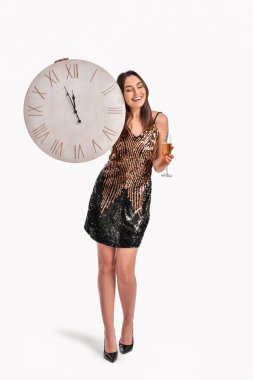 Gri arka planda saati ve şampanyası olan güzel bir genç kadın. Noel geri sayımı konsepti