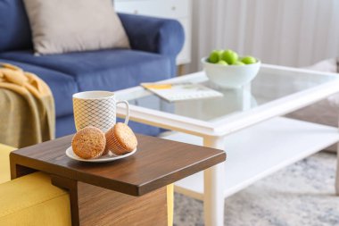 Bir fincan çay ve kekler odadaki koltukaltı masasında.