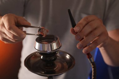 Man putting coal cubes on tobacco bowl, closeup