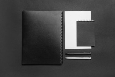 Koyu arkaplan üzerinde boş kağıt kağıtlar, defterler ve kalemlerle kompozisyon