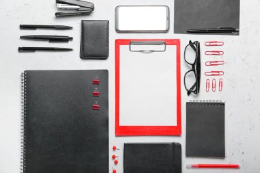 Composition with clipboard, mobile phone and stationary on light background