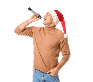 Mikrofonlu genç adam beyaz arka planda Noel şarkısı söylüyor.