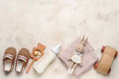 Bebek için bir şişe süt ve gri arka planda aksesuarlar.