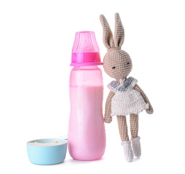 Bir şişe süt formülü ve beyaz arka planda oyuncak.