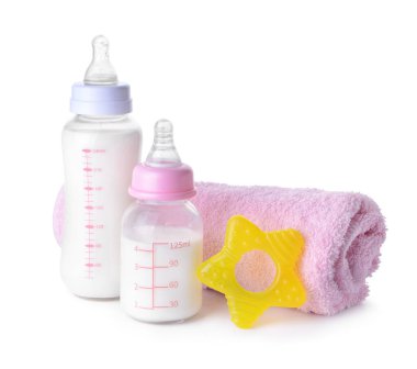 Bebek için süt şişeleri ve beyaz arka planda havlu.