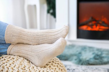 Evde elektrikli şöminenin yanında oturan genç bir kadın. Isınma mevsimi kavramı