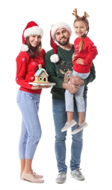 Beyaz arka planda zencefilli kurabiye evi olan mutlu bir aile. Noel kutlaması