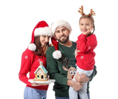 Beyaz arka planda zencefilli kurabiye evi olan mutlu bir aile. Noel kutlaması