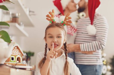 Küçük kız Noel arifesinde mutfakta sessizlik jesti yapıyor.