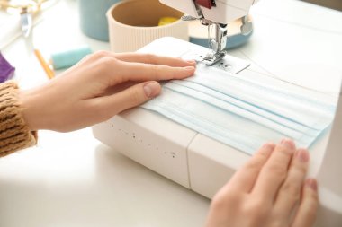 Atölyede koruyucu maskeler yapan kadın terzi.