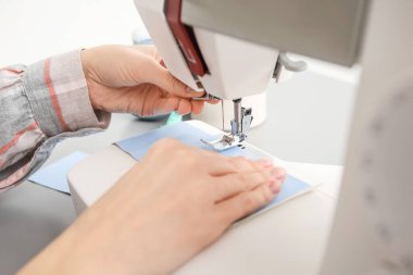 Atölyede koruyucu maskeler yapan kadın terzi.