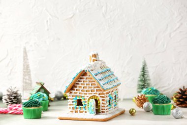 Noel dekorlu zencefilli kek evi ve masada kekler.