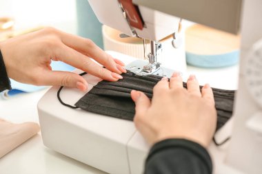 Atölyede koruyucu maskeler yapan kadın terzi.