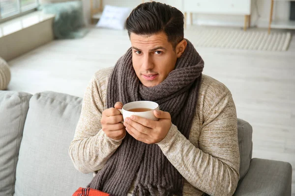 暖かい服を着た若い男と自宅でお茶を飲みます 暖房期の概念 — ストック写真