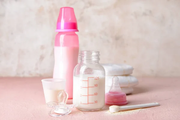 Bottle of baby milk formula and accessories on table