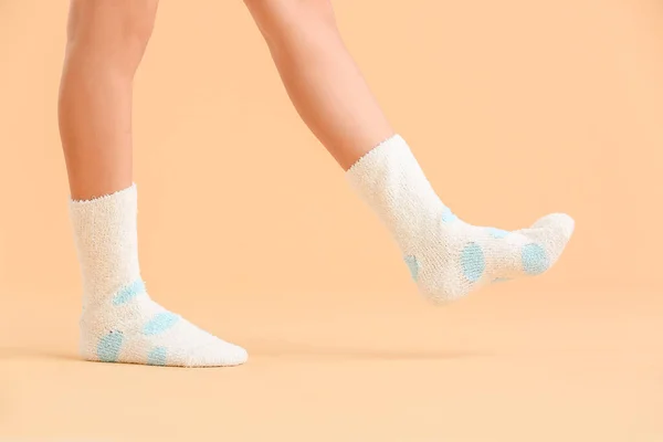 Legs of young woman in socks on color background