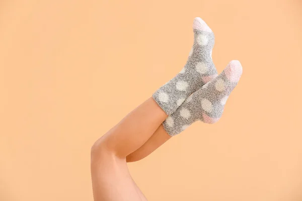 Legs of young woman in socks on color background