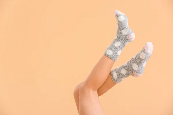 Legs of young woman in socks on color background