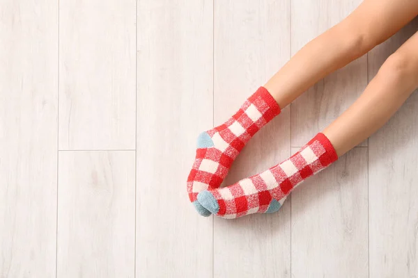 Legs of young woman in socks on wooden background