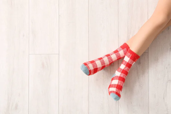 Legs of young woman in socks on wooden background