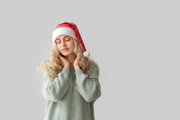 穿着浅色背景的圣诞老人帽的年轻漂亮女子 — 图库照片