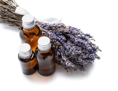 Beyaz zemin üzerinde lavanta yağı bulunan şişeler