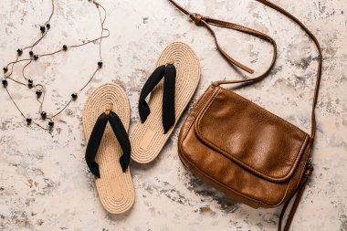 Şık bir kadın çantası ve arka planda parmak arası terlikler.
