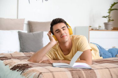 Genç adam yatak odasında müzik dinliyor.