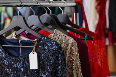 Askılarda giysi ve boş kağıt etiket