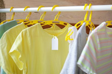 Askılarda giysi ve boş kağıt etiket