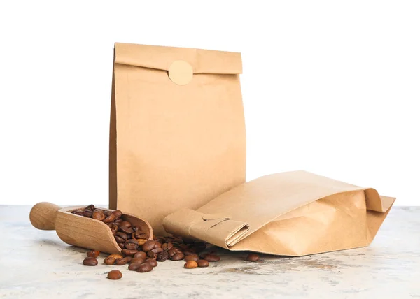 Taschen Mit Kaffeebohnen Und Schaufel Auf Tisch Vor Weißem Hintergrund — Stockfoto