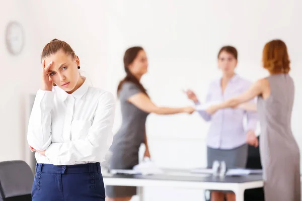 Stressed woman with headache and noisy people in office